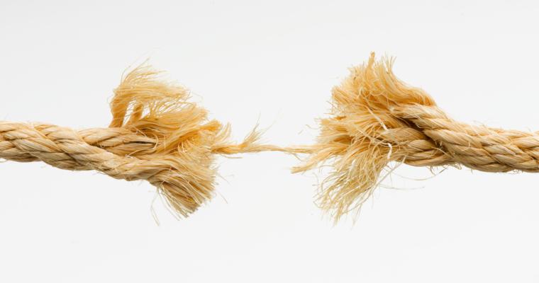 A frayed rope breaking in the middle against a white background